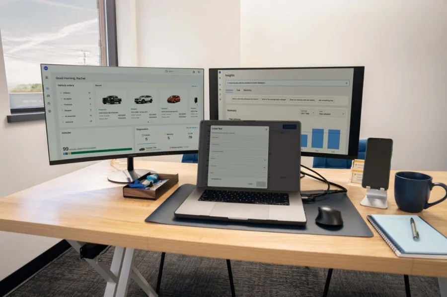OnStar Fleet Intelligence dashboard shown on two monitors and a laptop on an office desk